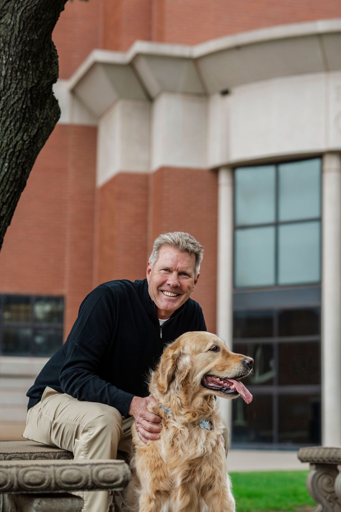 Michael Coulson kneeling beside his golden retriever